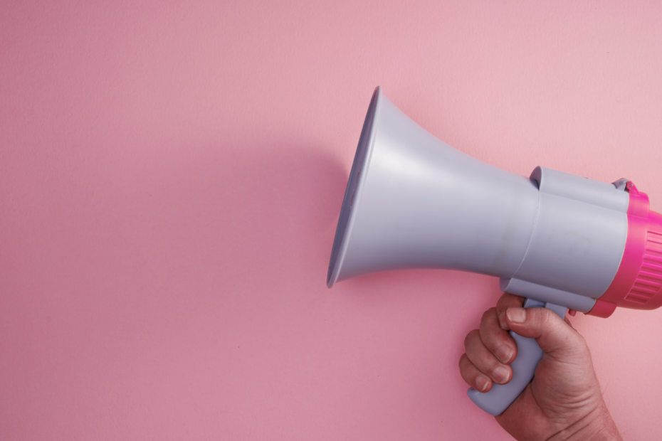 Hand holding a megaphone against a pink background