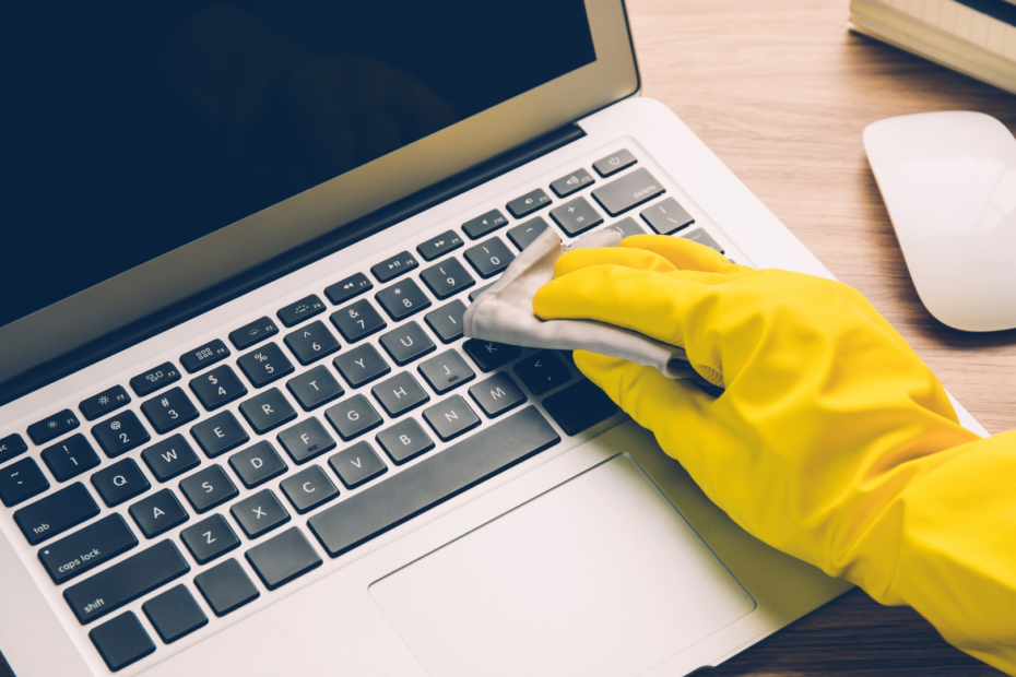 gloved hand wiping down laptop